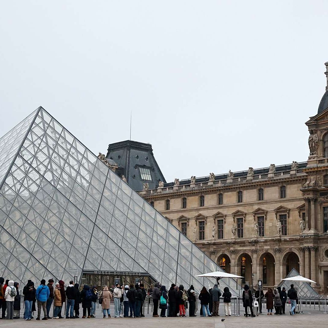 Personas cerca de la pirámide de cristal del Museo del Louvre