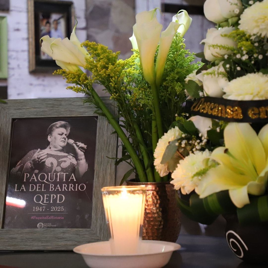 Fotografía de Paquita la del Barrio acompañada de flores y una vela en CDMX