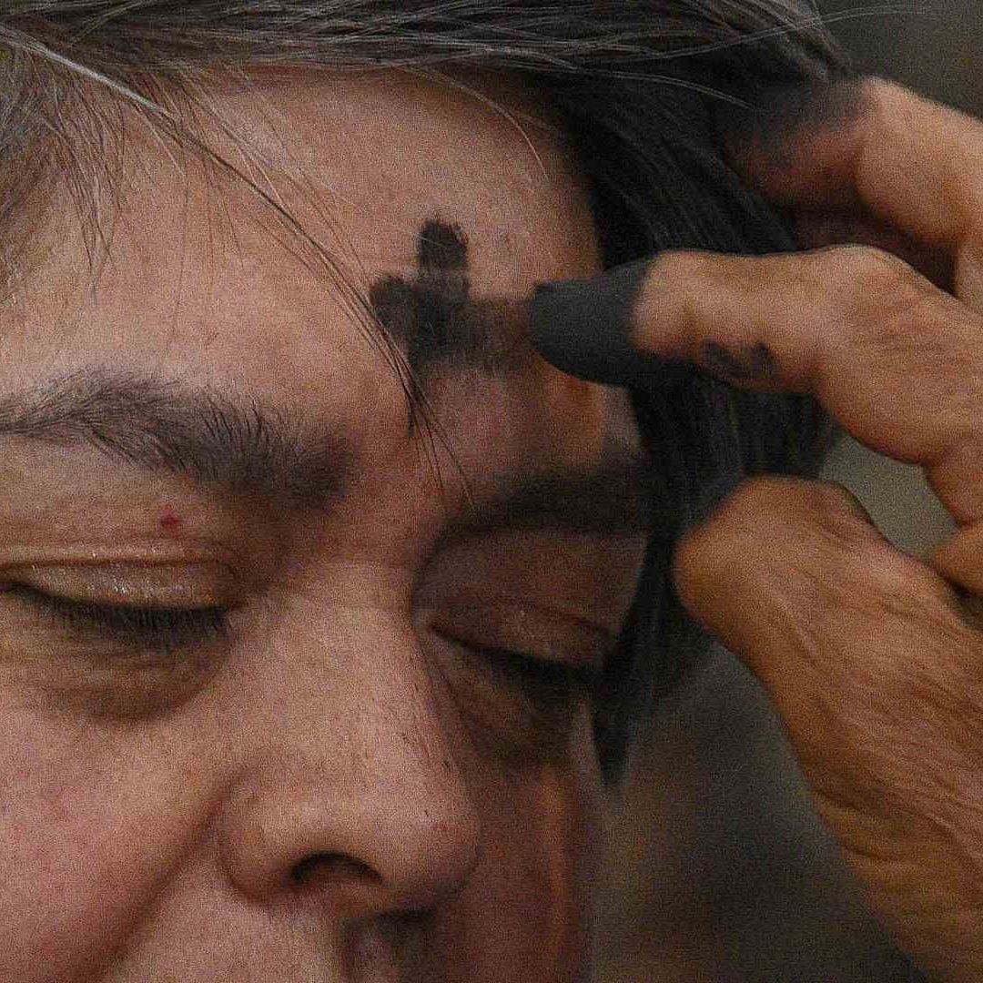 Sacerdote coloca cruz de ceniza a una mujer en la catedral de Toluca