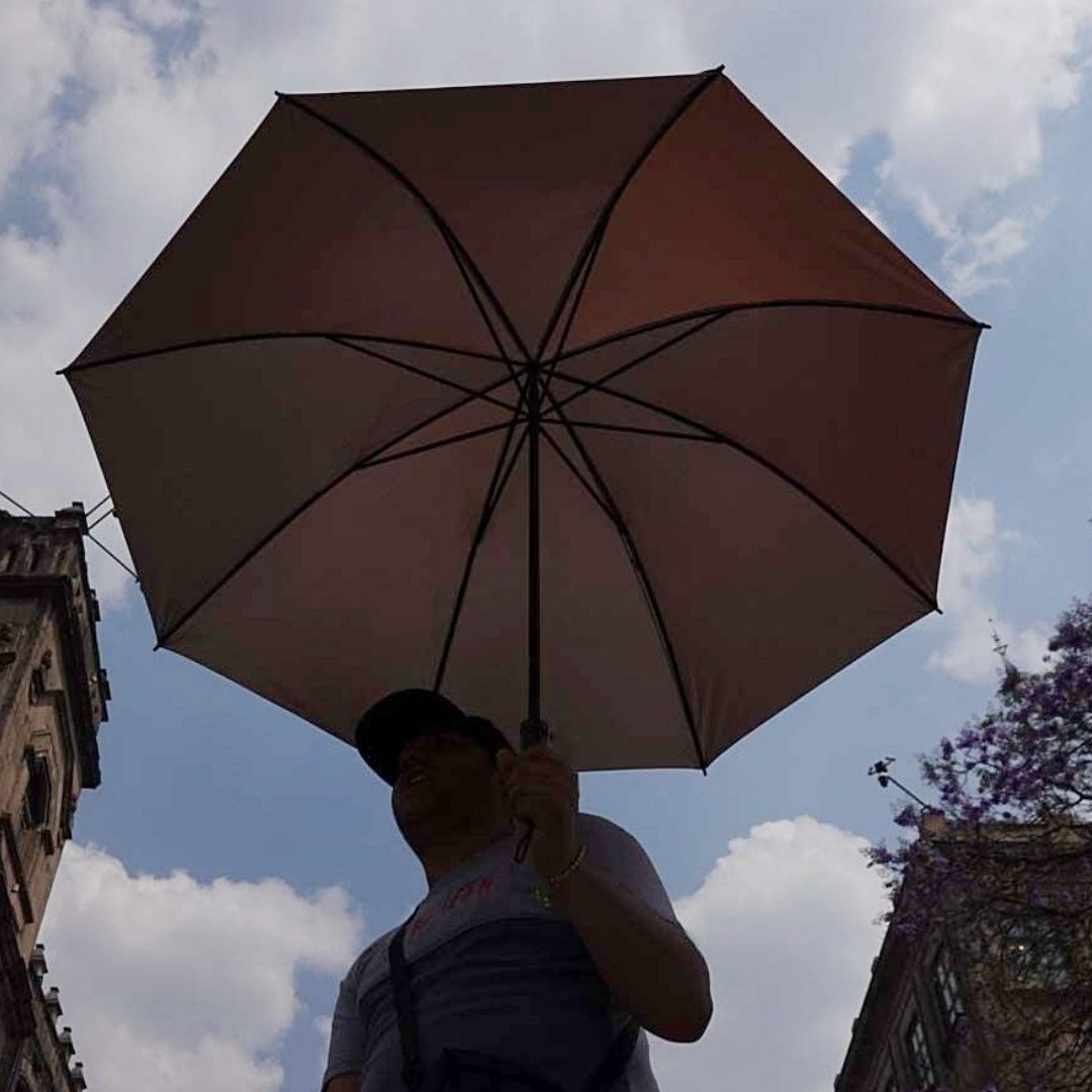 Capitalinos se cubren de los rayos del sol en el Zócalo CDMX
