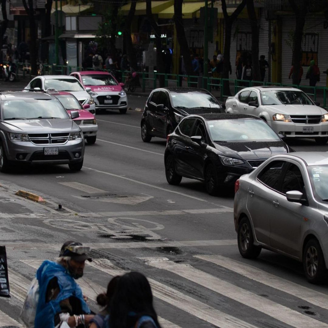 Los coches que sí circulan por calles de la CDMX mientras personas esperan cruzar la calle.