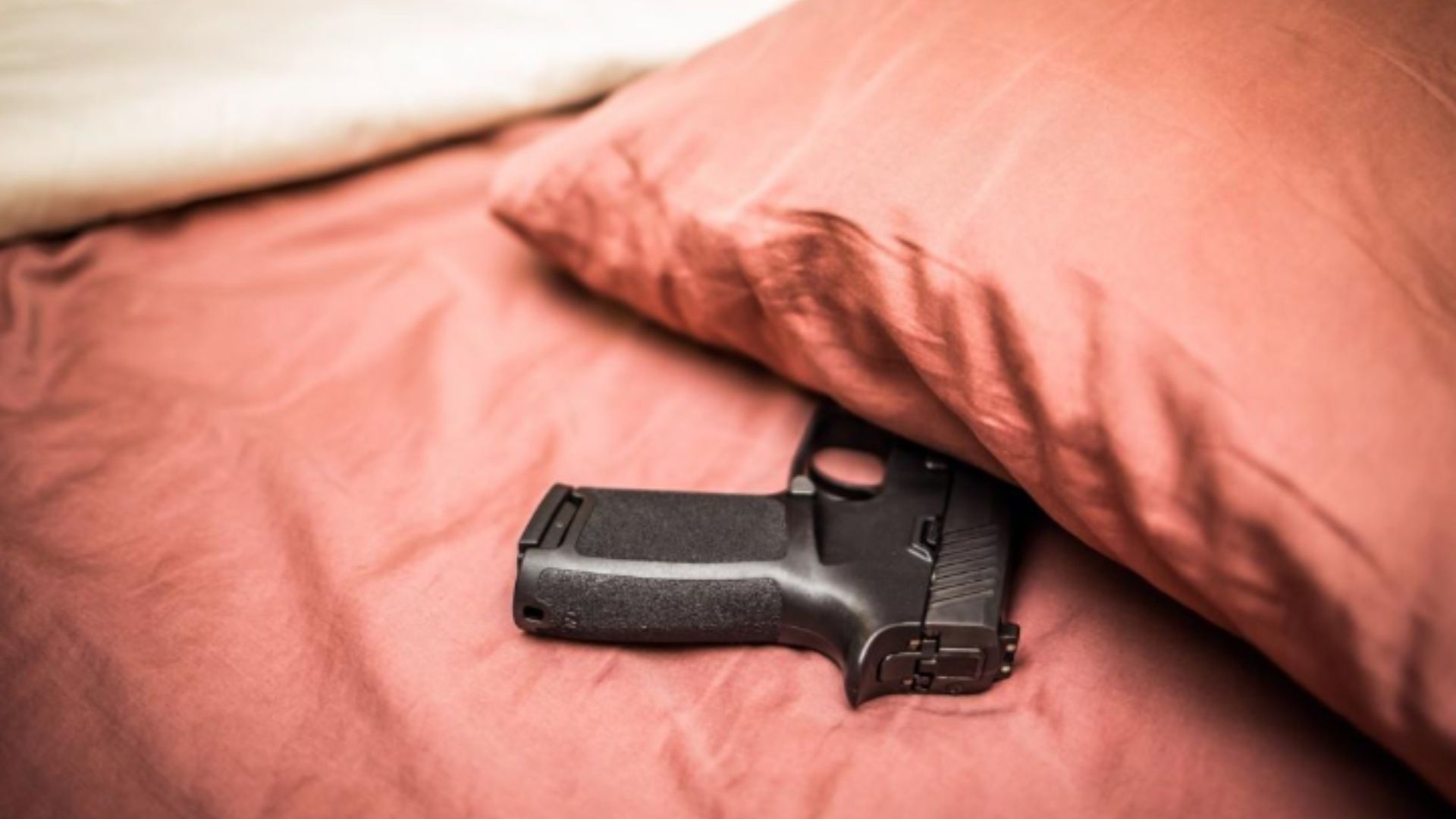 Imagen ilustrativa de un arma de fuego en la cama