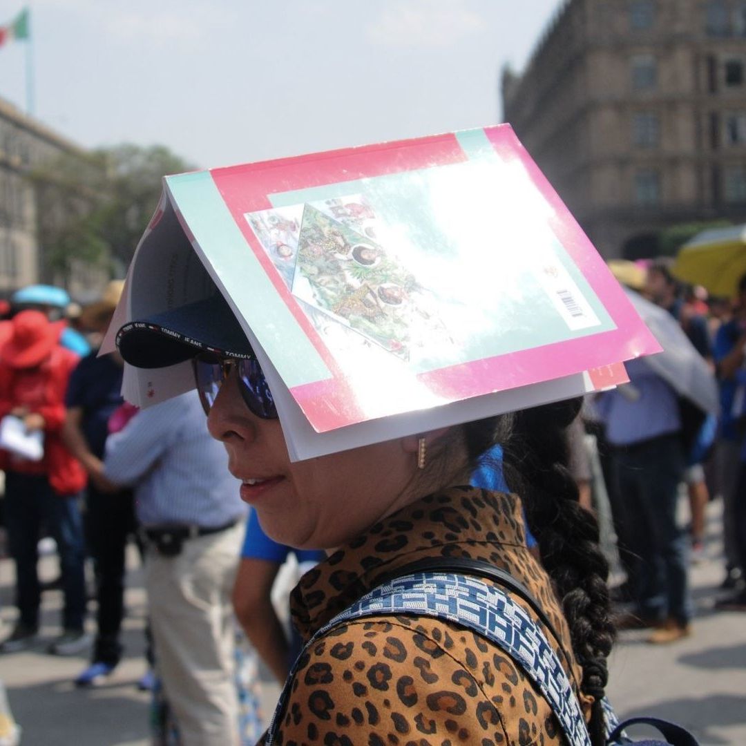Una mujer utiliza un libro para protegerse del sol en la Ciudad de México, 15 de abril de 2024