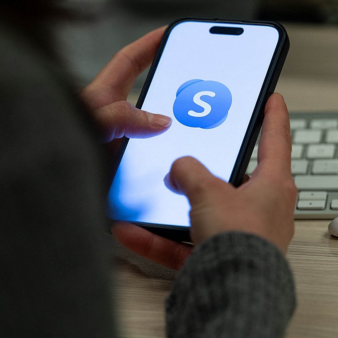 Una persona sostiene un celular que muestra la aplicación Skype