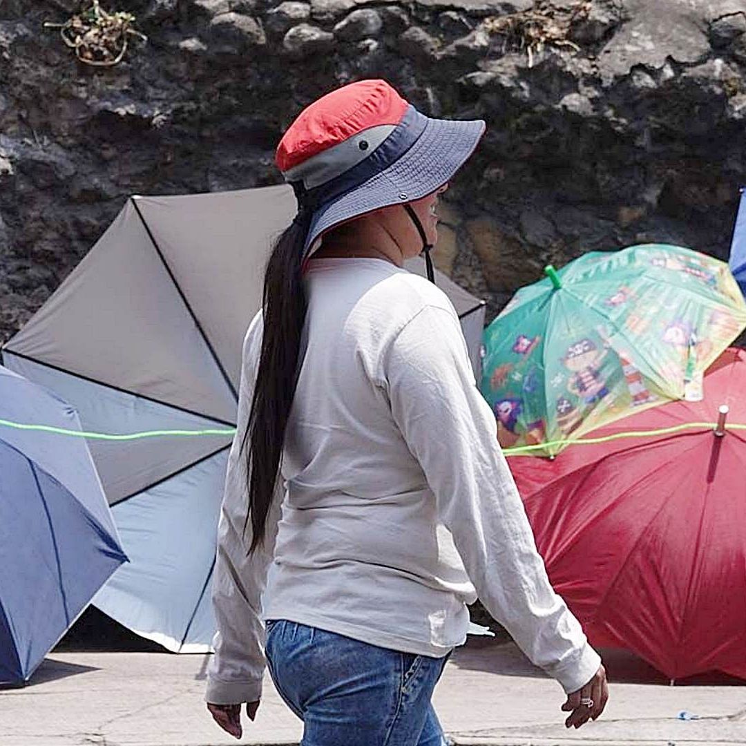 Mujer se protege con sombrero de las altas temperaturas en CDMX
