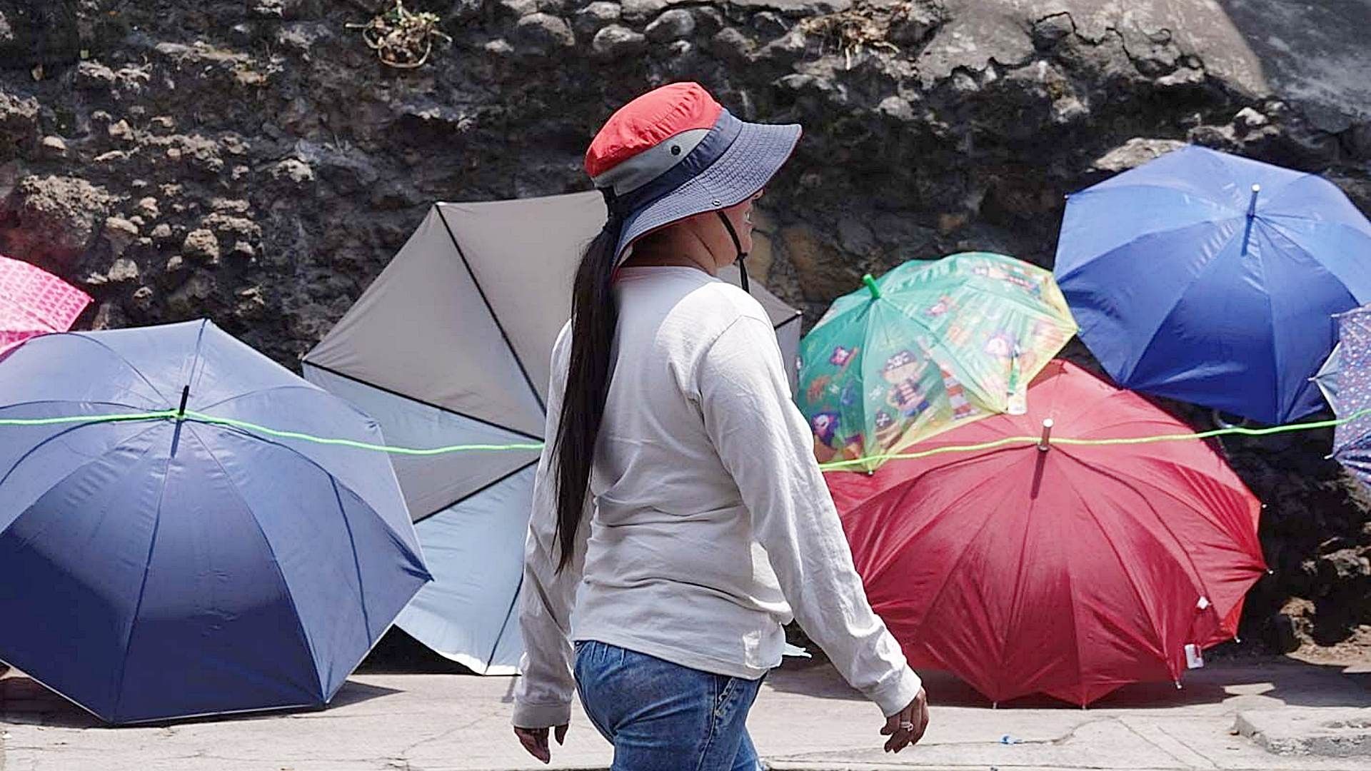 Mujer se protege con sombrero de las altas temperaturas en CDMX