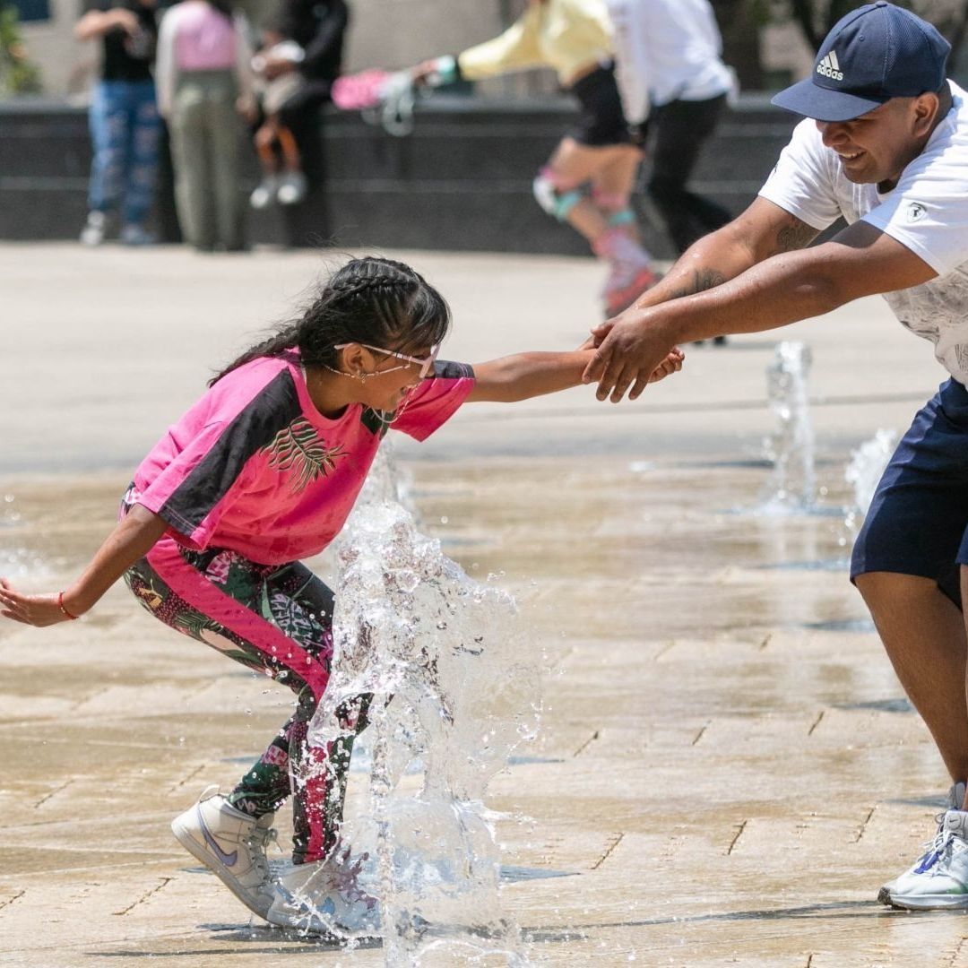 Una niña y su padre refescádose en las fuentes del Monumento a la Revolución