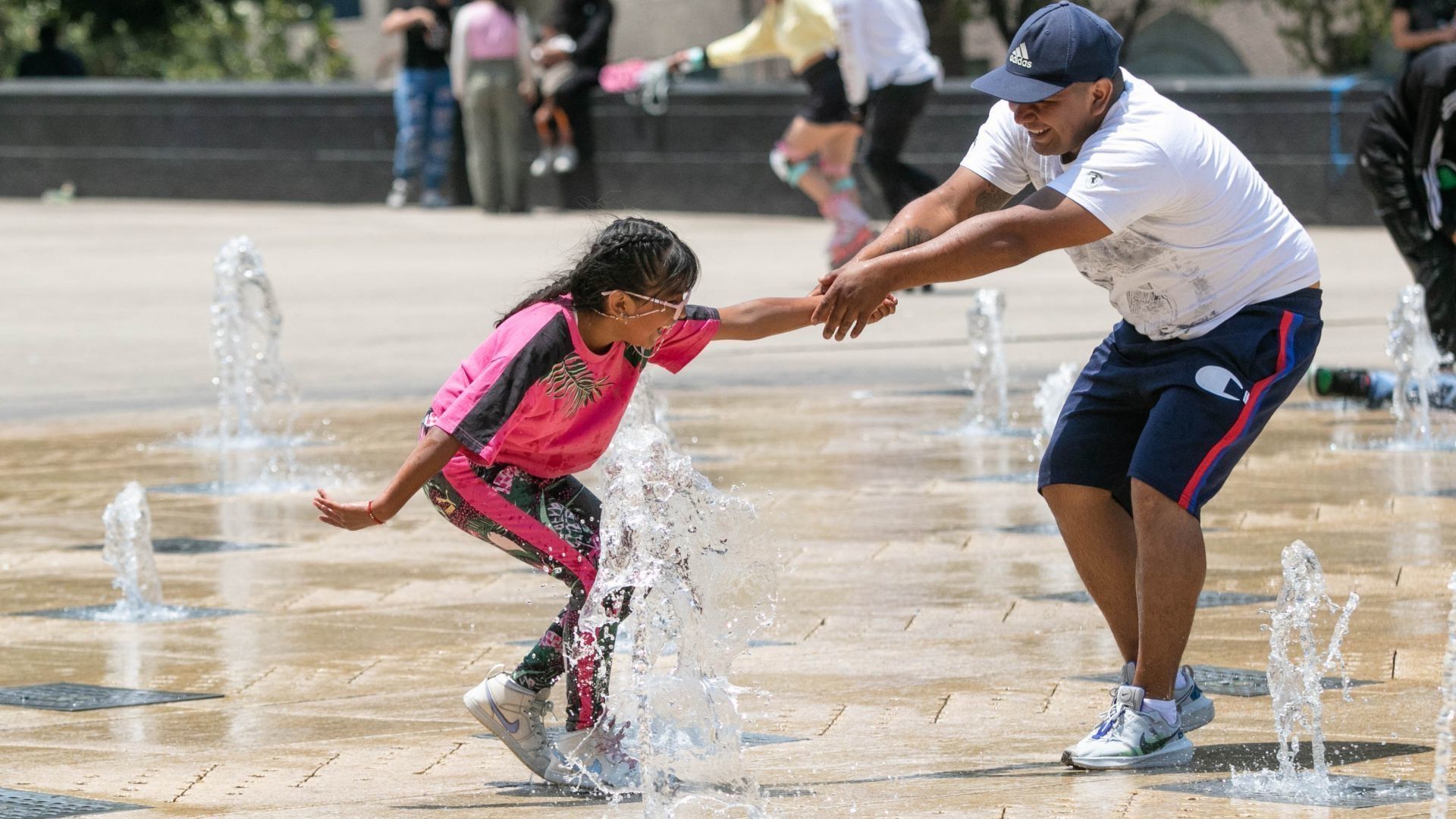 Una niña y su padre refescádose en las fuentes del Monumento a la Revolución