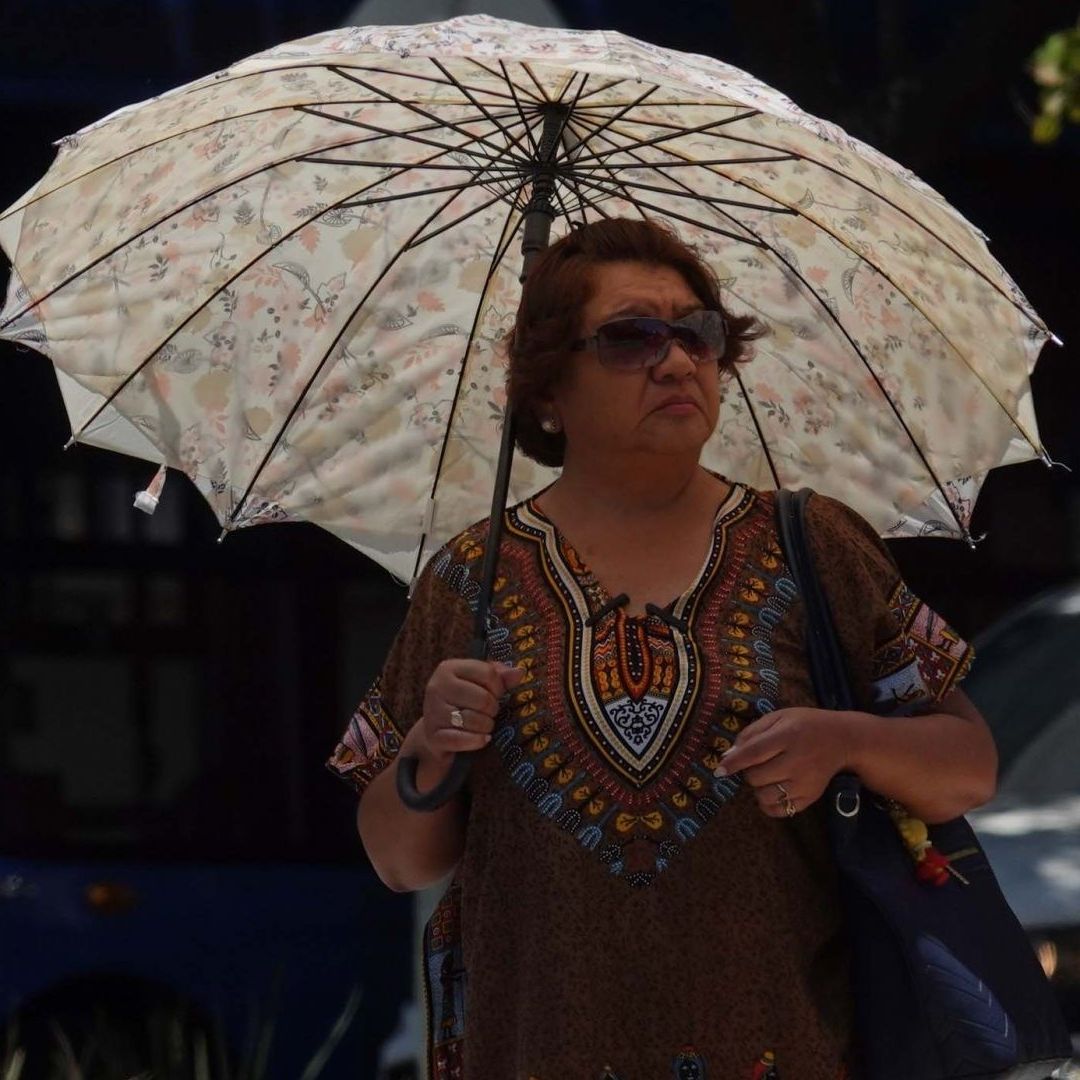 Una mujer se protege de los rayos del Sol en la Alameda Central