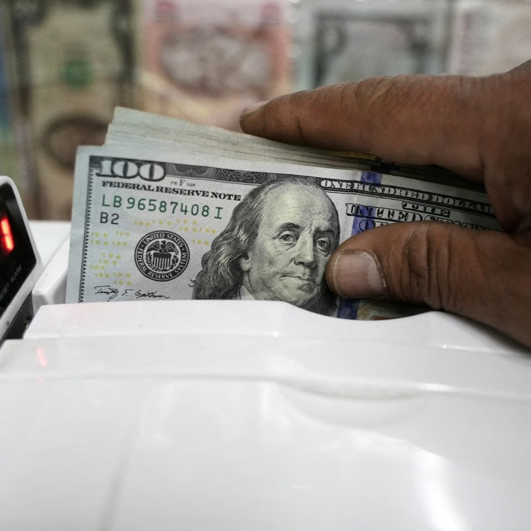 una persona usa máquina para contar billetes de 100 dólares