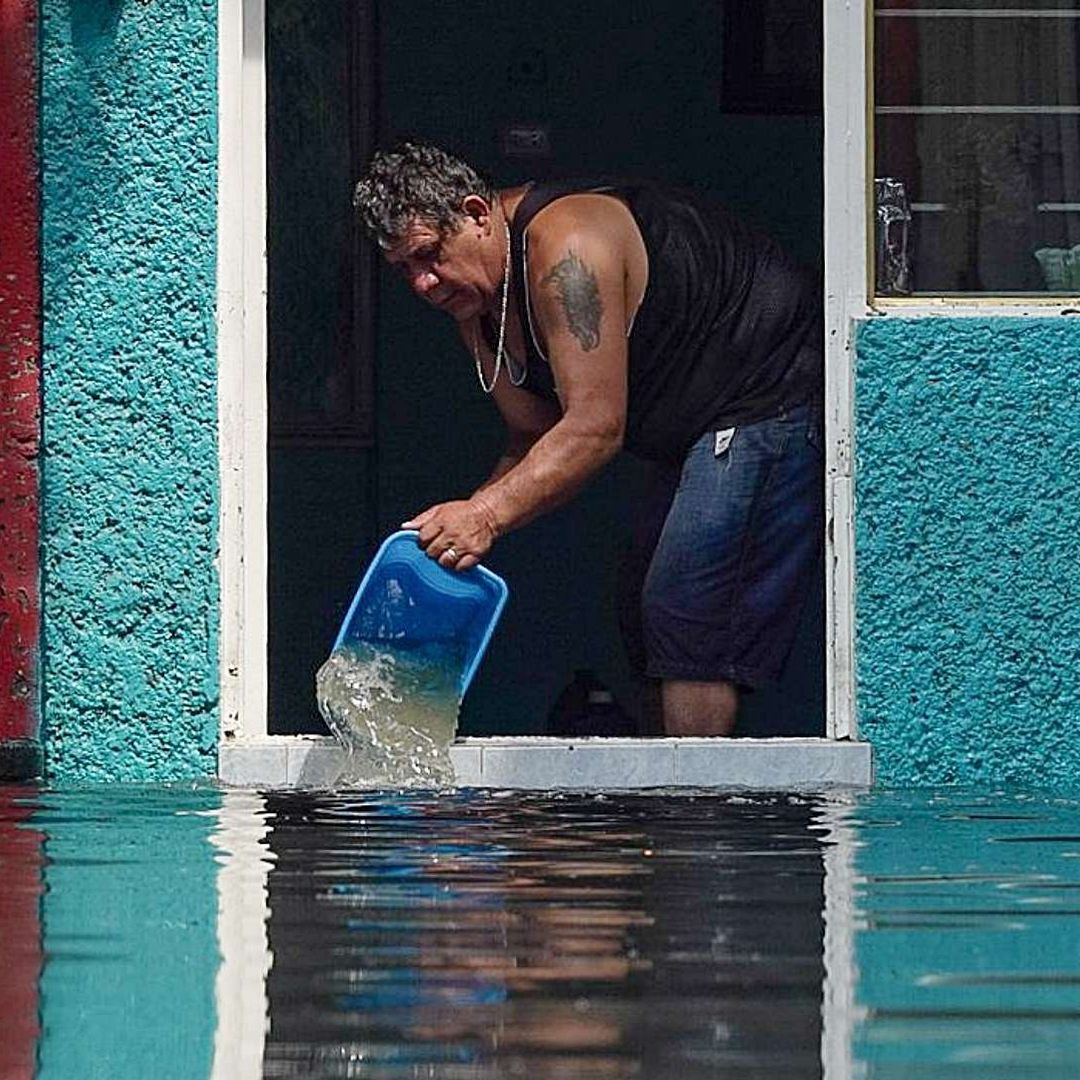 Hombre usa un bote para sacar el agua de su casa, que se inundó en Iztapalapa