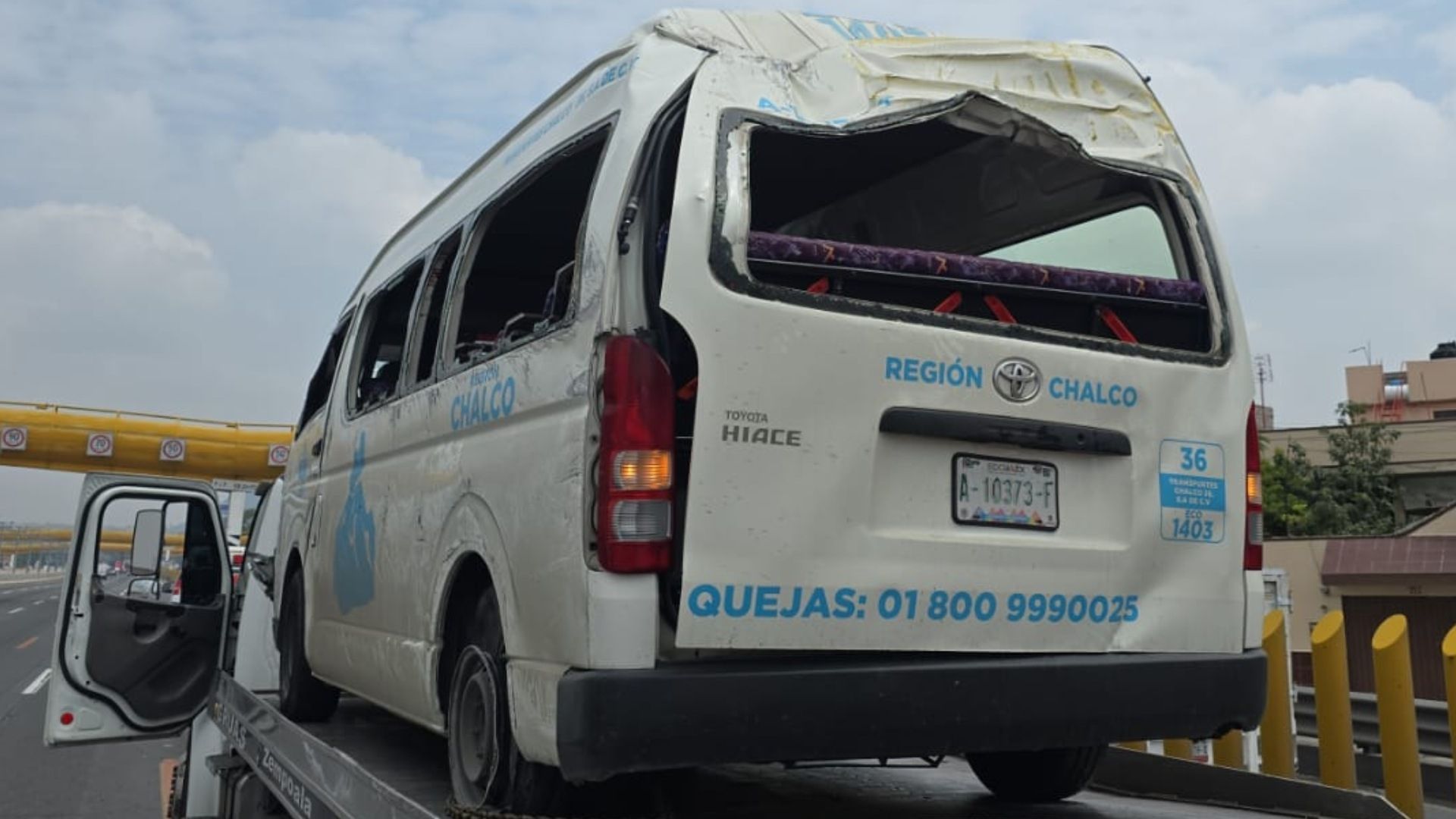 Combi destruida luego de accidente, sobre una plataforma de grúa