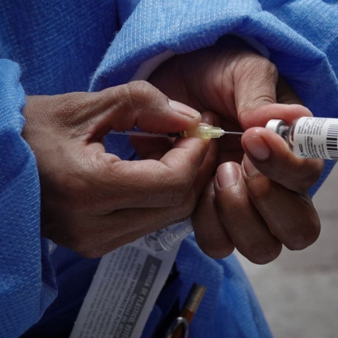 persona llena jeringa con frasco para vacuna
