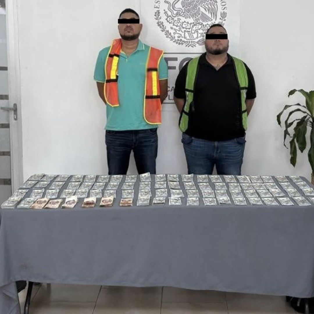 Oficiales flanquean a dos personas detenidas con 100 mil dólares en efectivo en Nuevo León