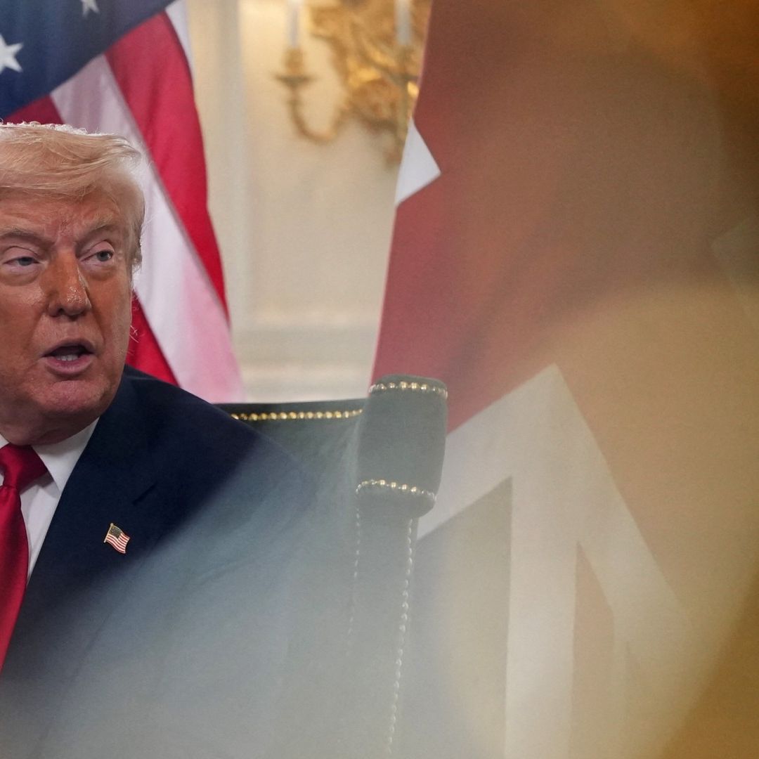 Donald Trump sentado y detrás de él una bandera de Estados Unidos