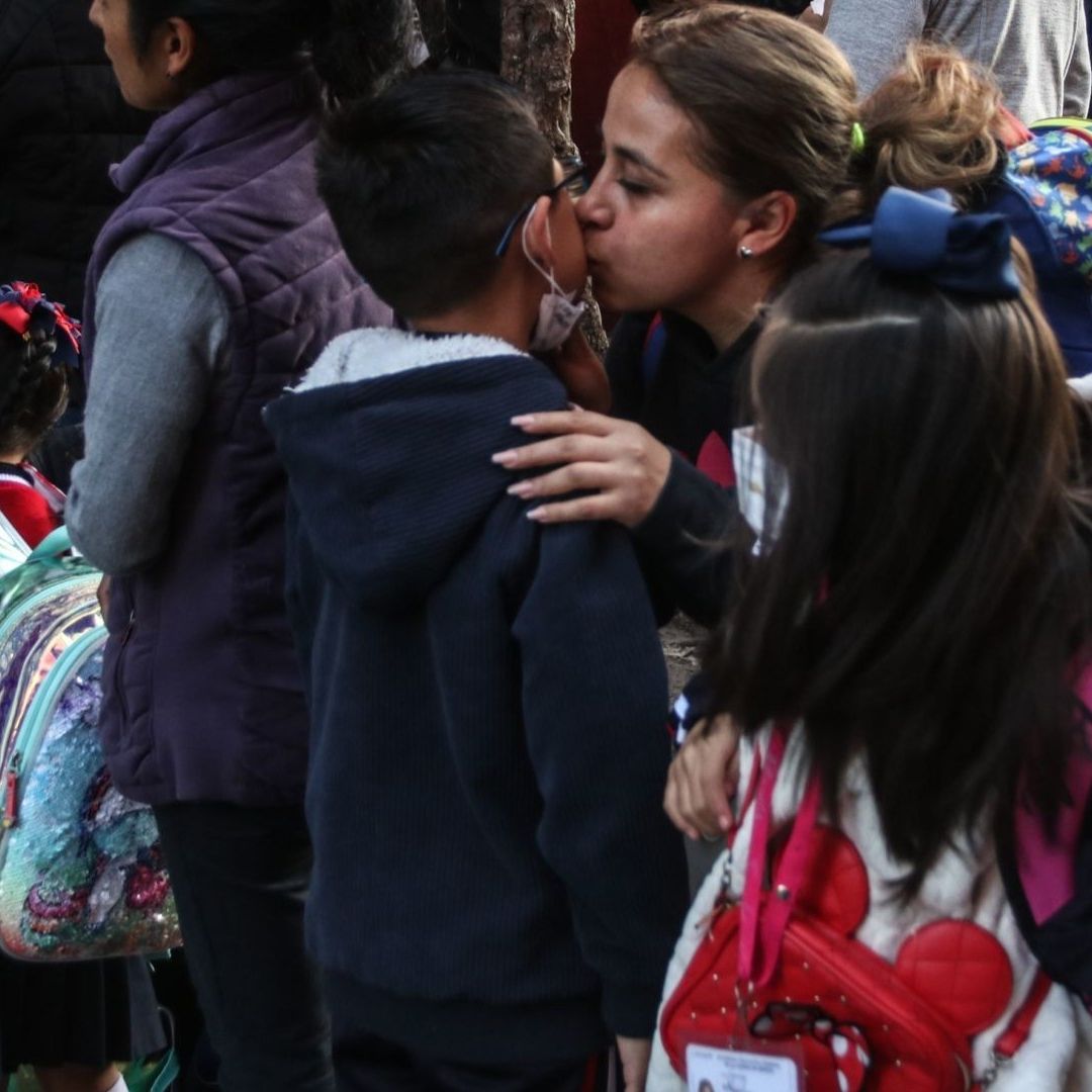 Mujer despide a niño afuera de la escuela