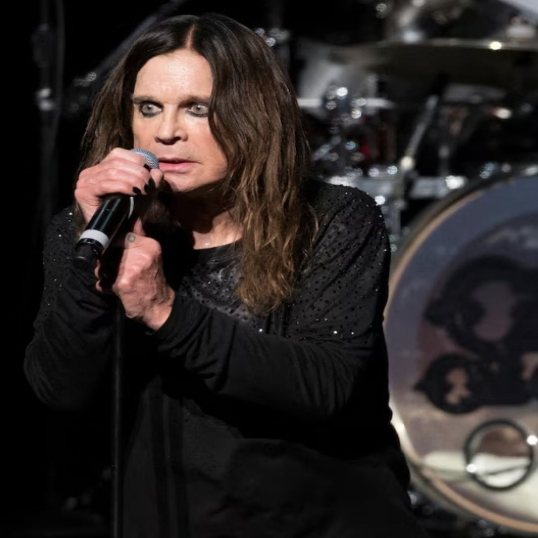 Ozzy Osbourne durante un concierto, se encuentra al lado de un instrumento musical que dice su nombre.
