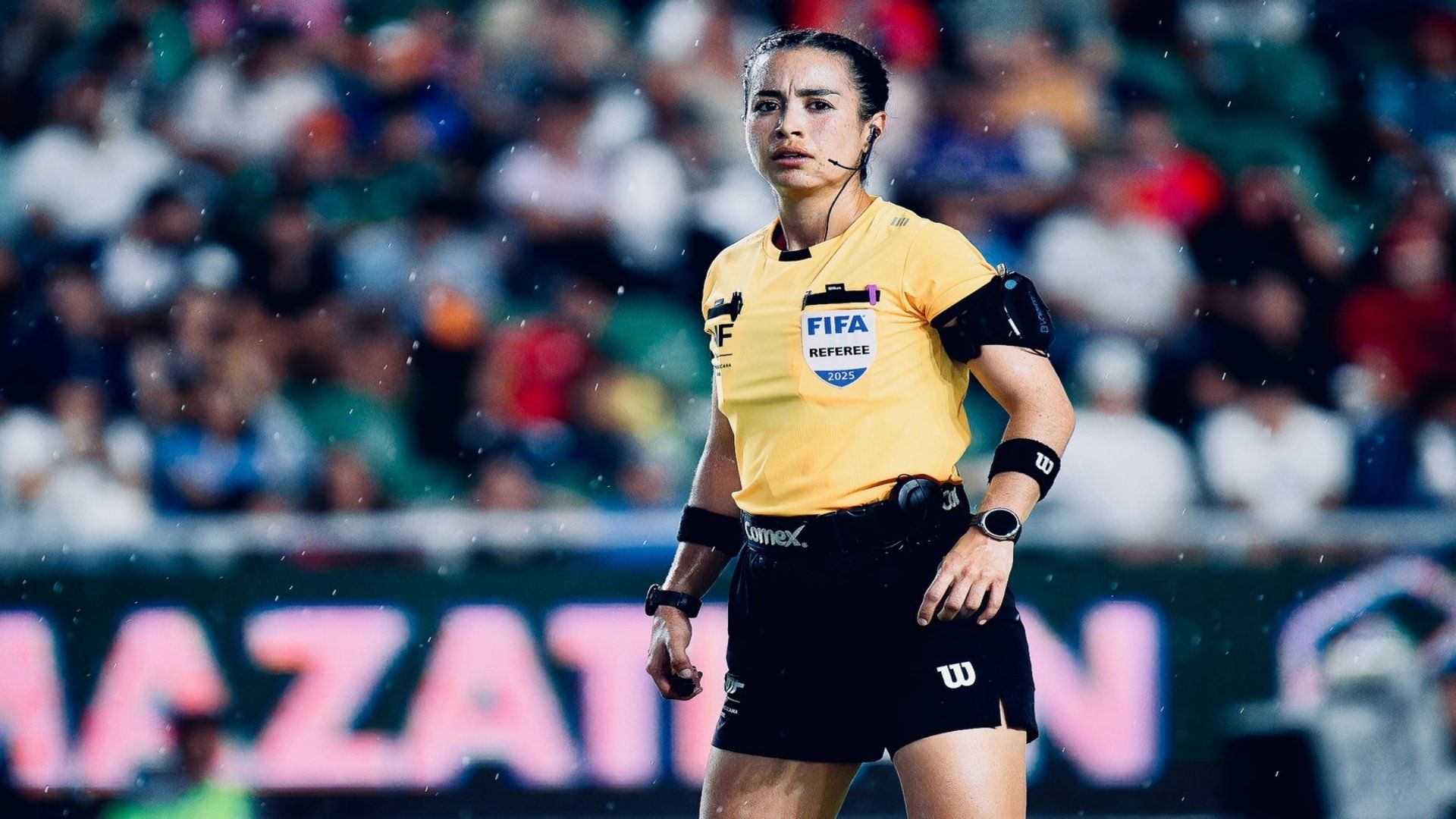 Katia Itzel García, arbitra mexicana, durante un partido. Usa uniforme amarillo con negro.