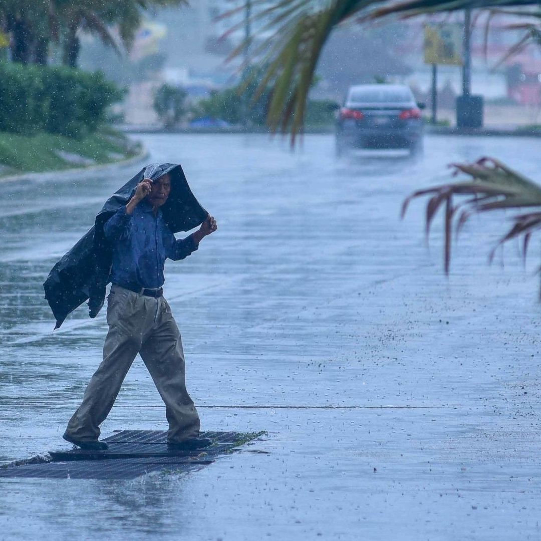 Persona camina bajo la lluvia en calle de Acapulco