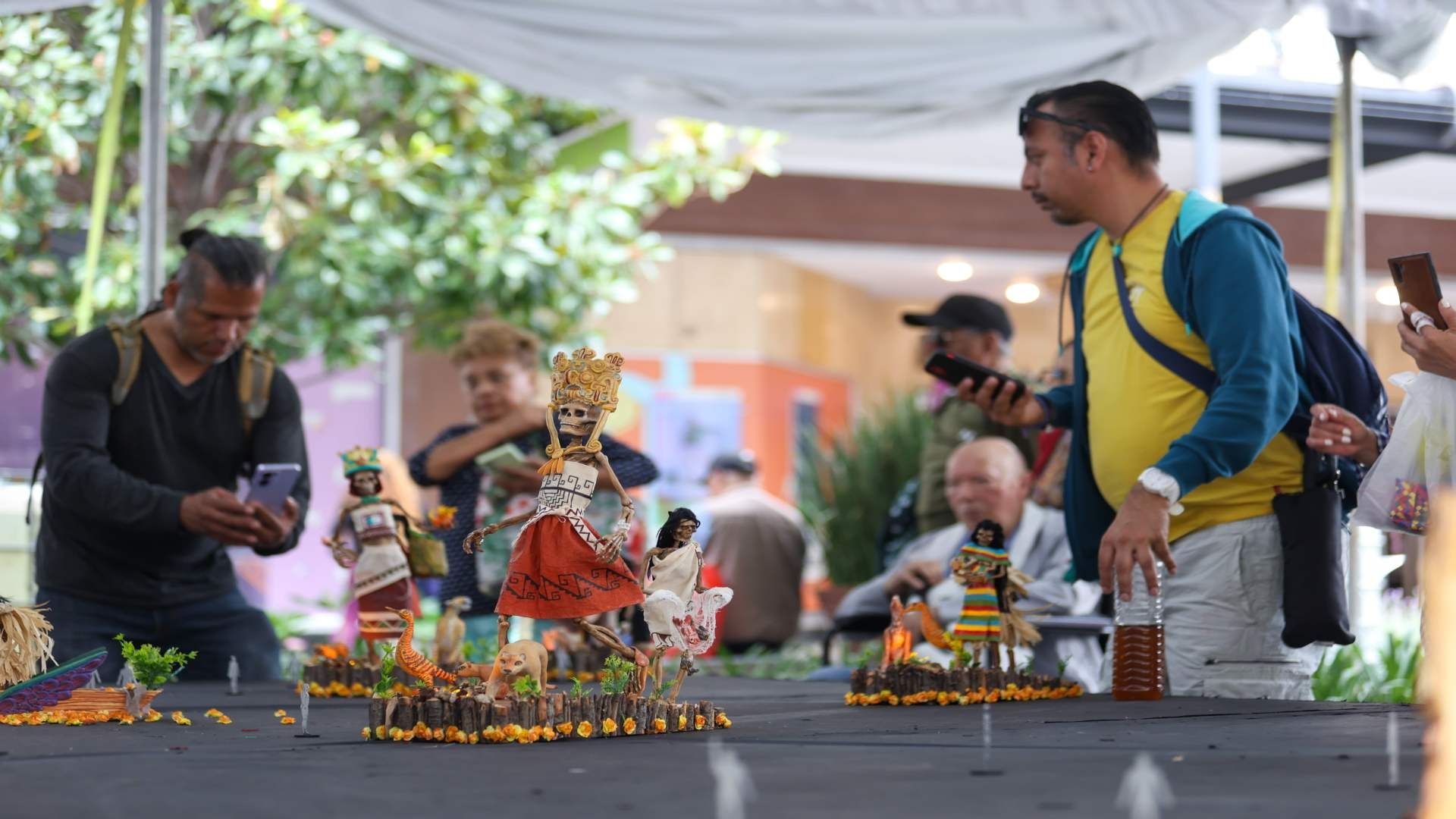 Personas observando una pfrenda temática de Día de Muertos.