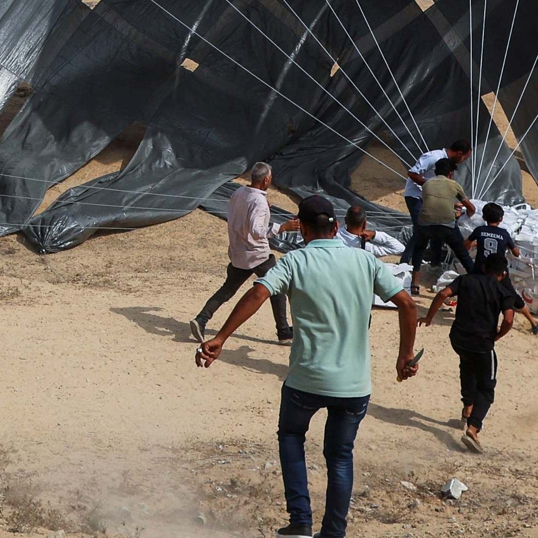 Palestinos corren a recoger alimentos mientras se lanzan paquetes de ayuda desde un avión