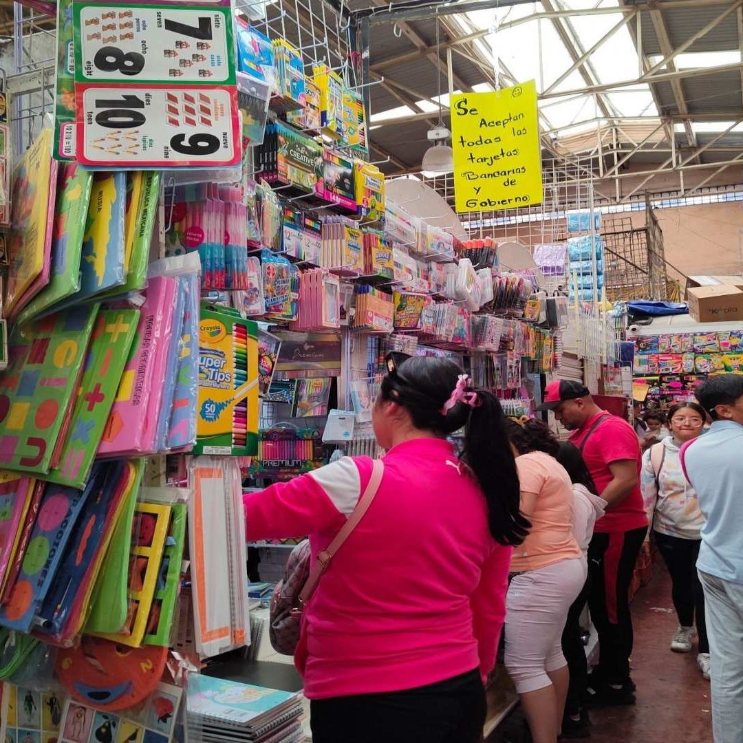 Varias personas comaprando útiles escoalres en un mercado de la CDMX.