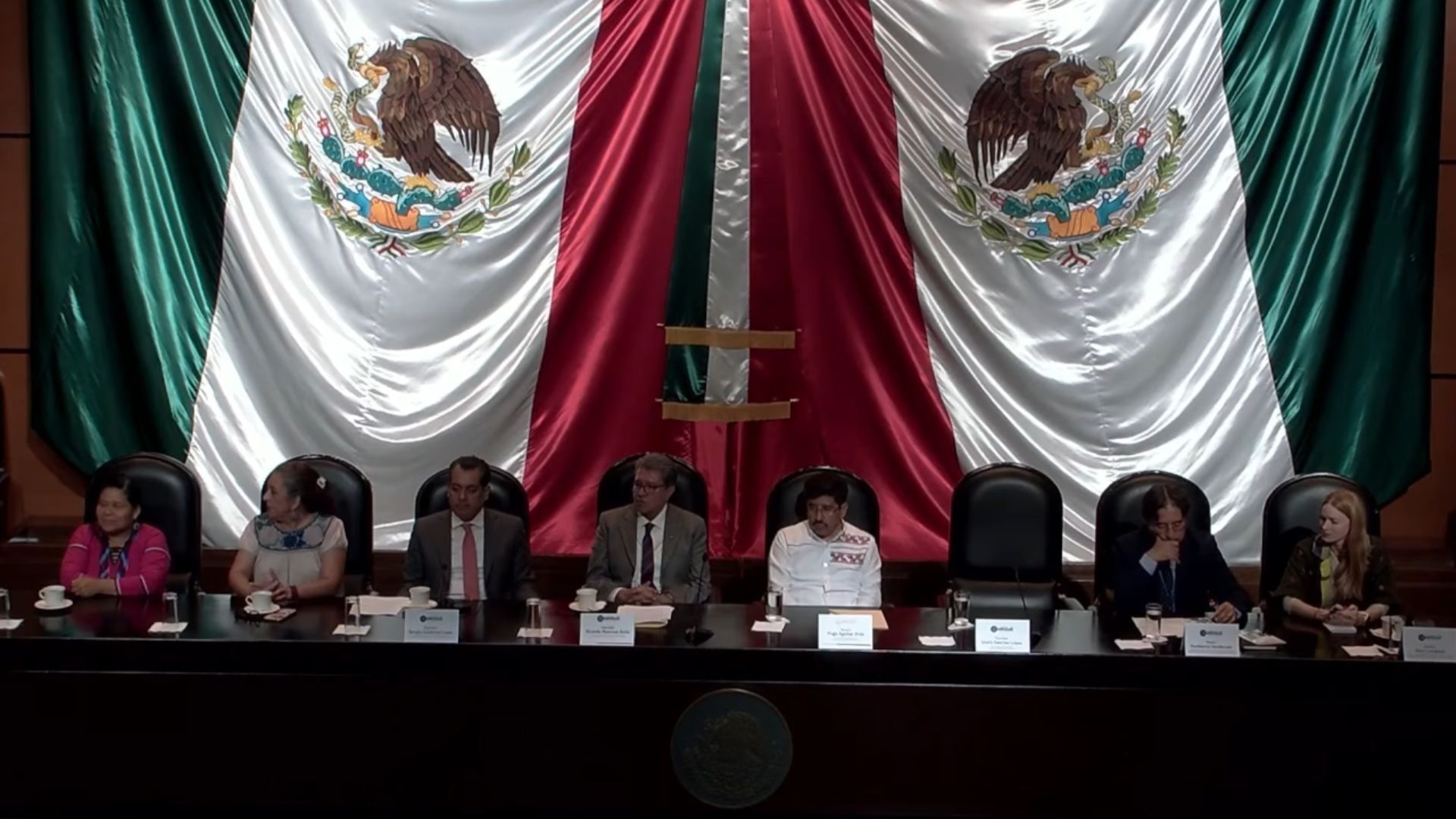 Una bandera de México de gran tamaño detrás del ministro presidente de la Corte.