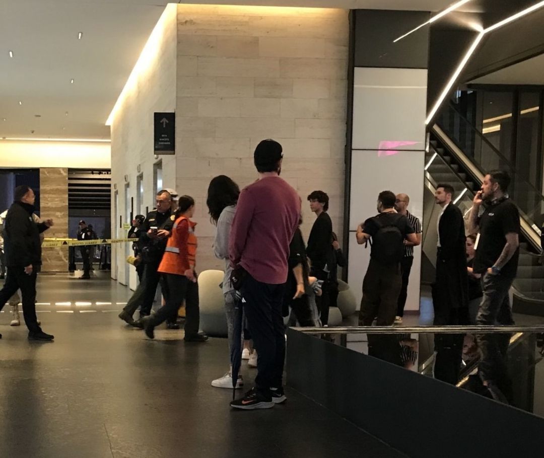 Elementos de la Policía y personas caminan cerca de elevadores.