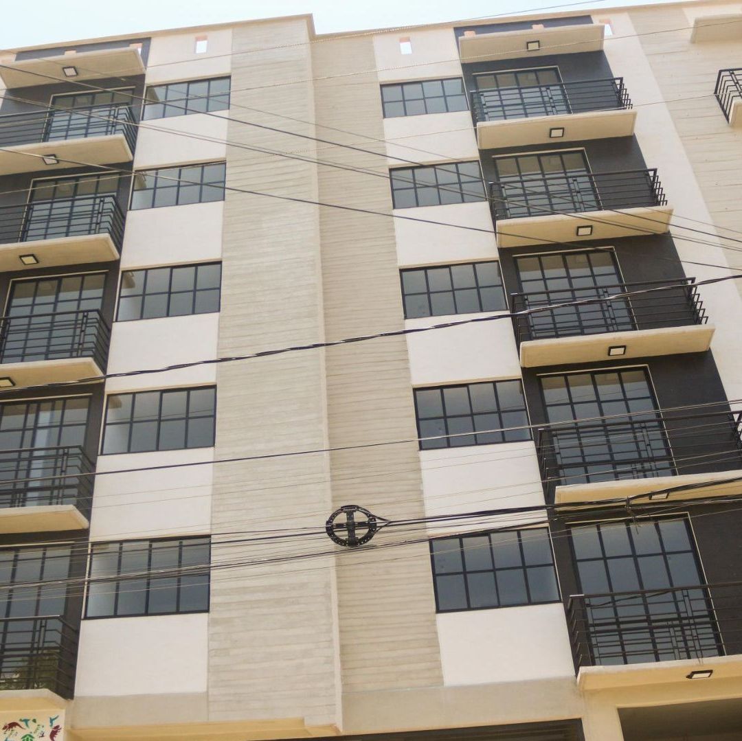 Edificio de color beige, con balcones de color gris con negro.