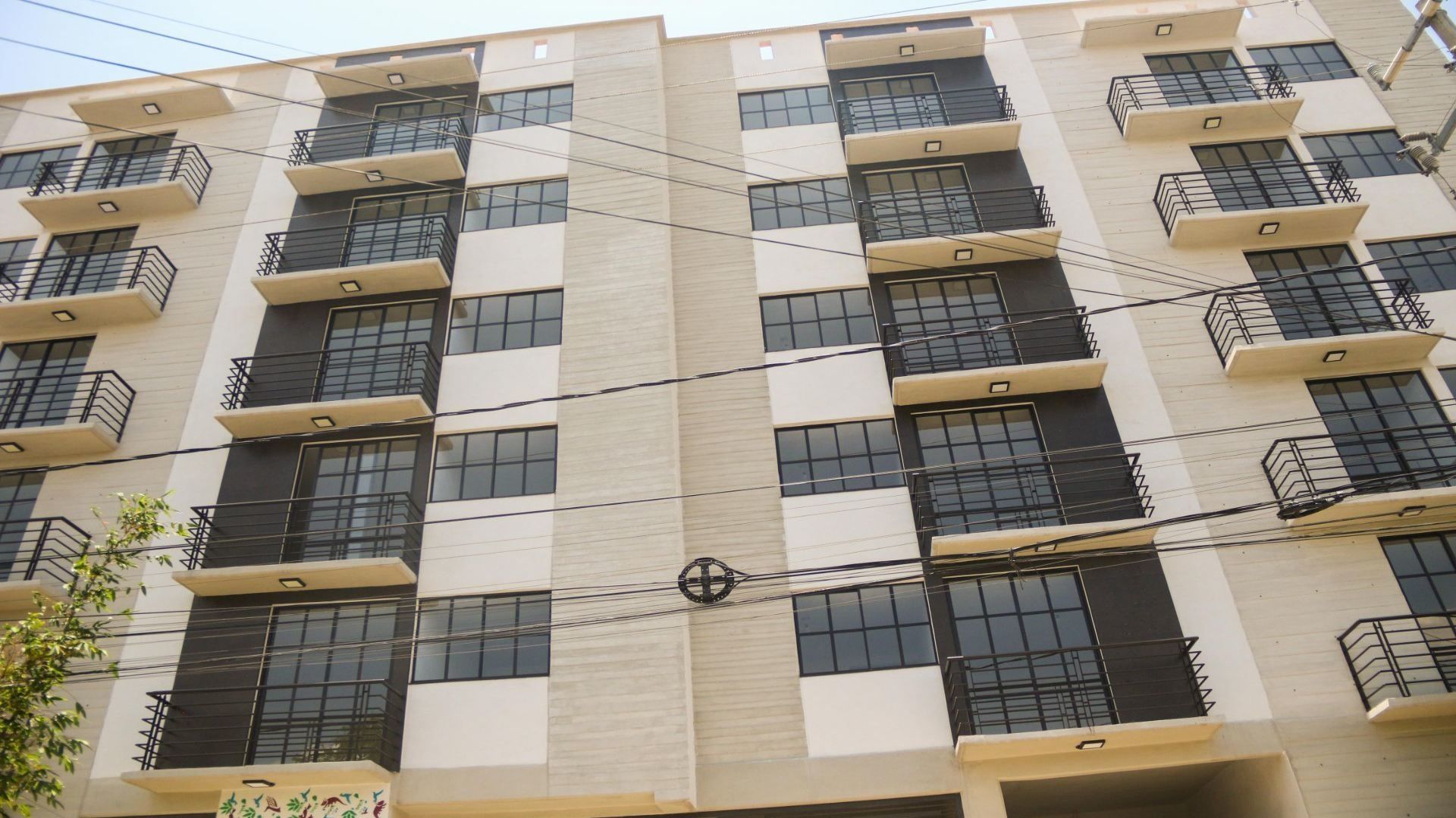 Edificio de color beige, con balcones de color gris con negro.