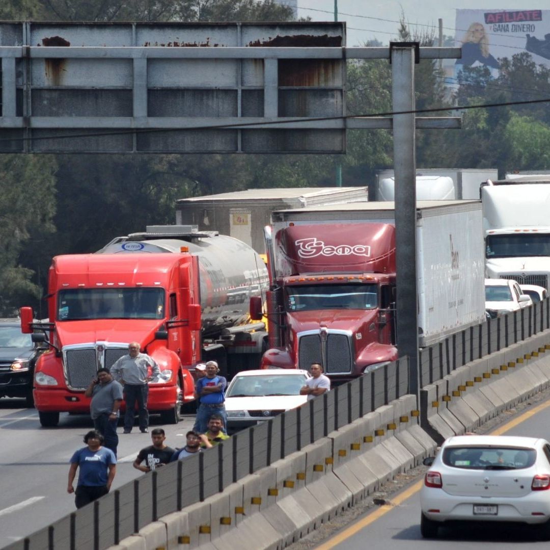 Un camión de color rojo de tamaño grande resalta entre el tráfico de una carretera en México.