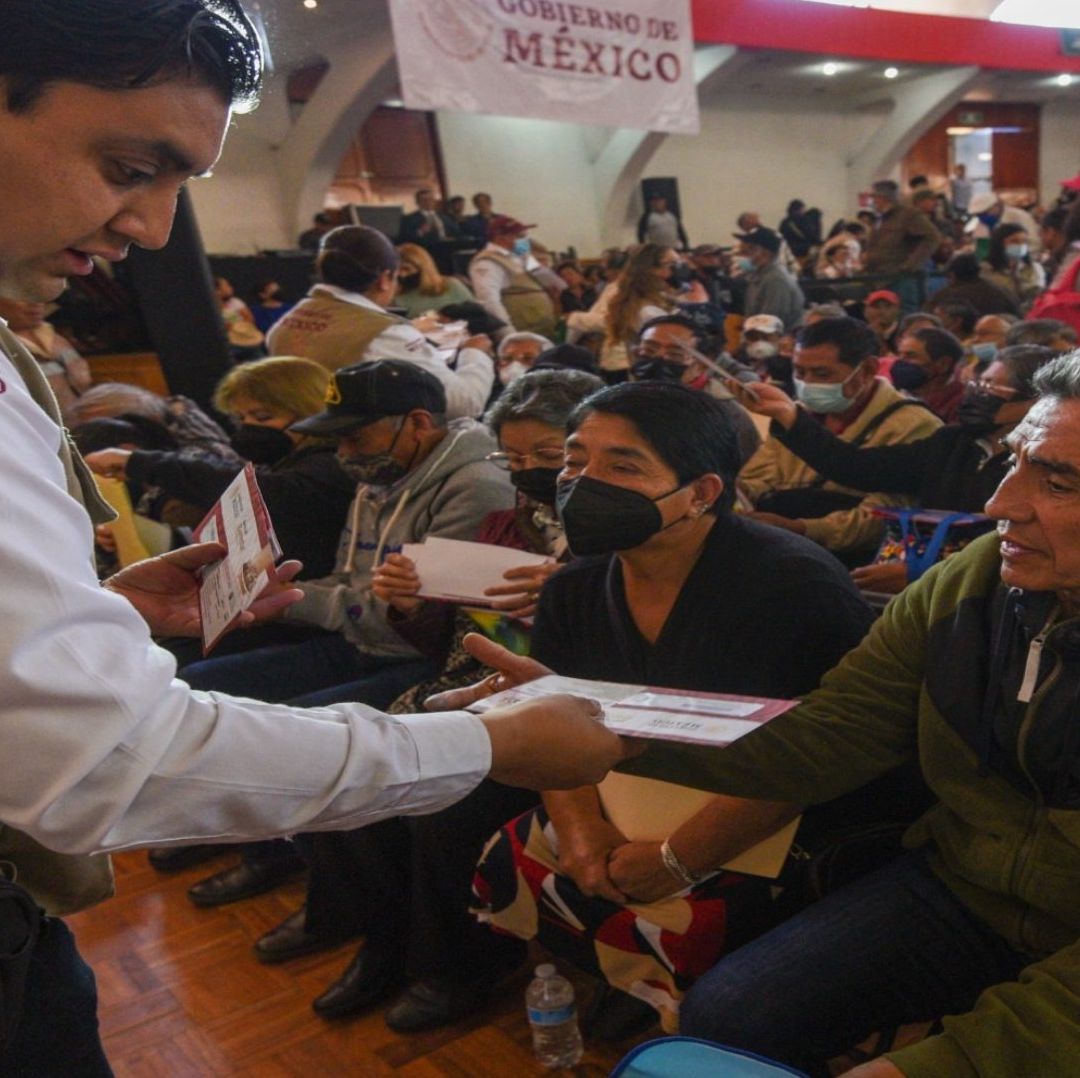 Un trabajador del gobierno le entrega una tarjeta a una persona adulta mayor.