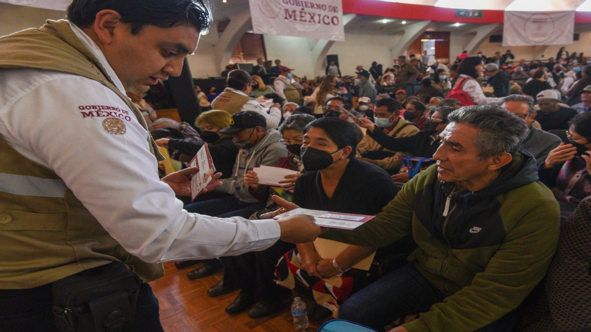 Un trabajador del gobierno le entrega una tarjeta a una persona adulta mayor.