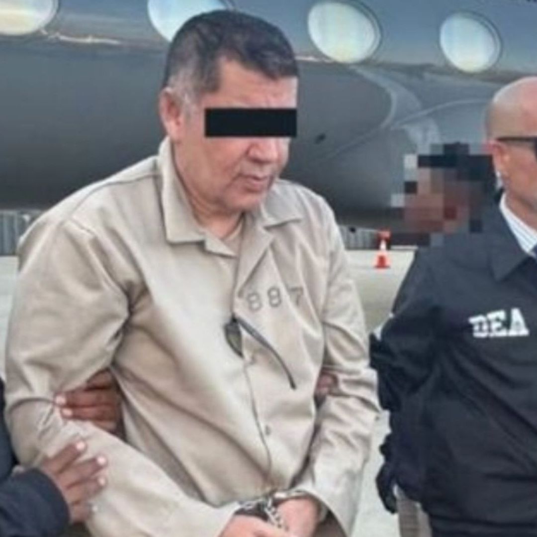 Un hombre es escoltado por los elementos; sus ojos están cubiertos con una cinta negra.