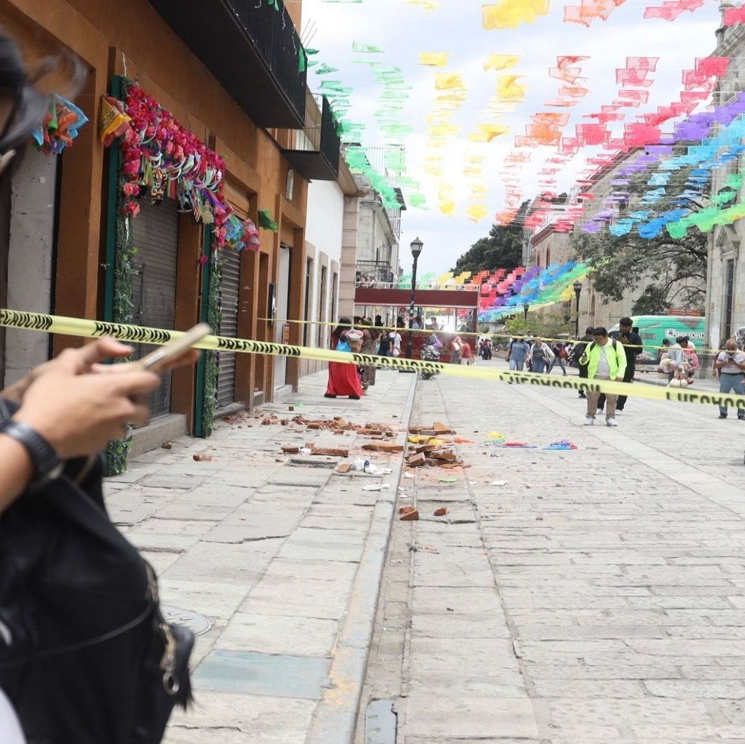 Una mujer con un celular frente a una cinta amarilla de precaución.