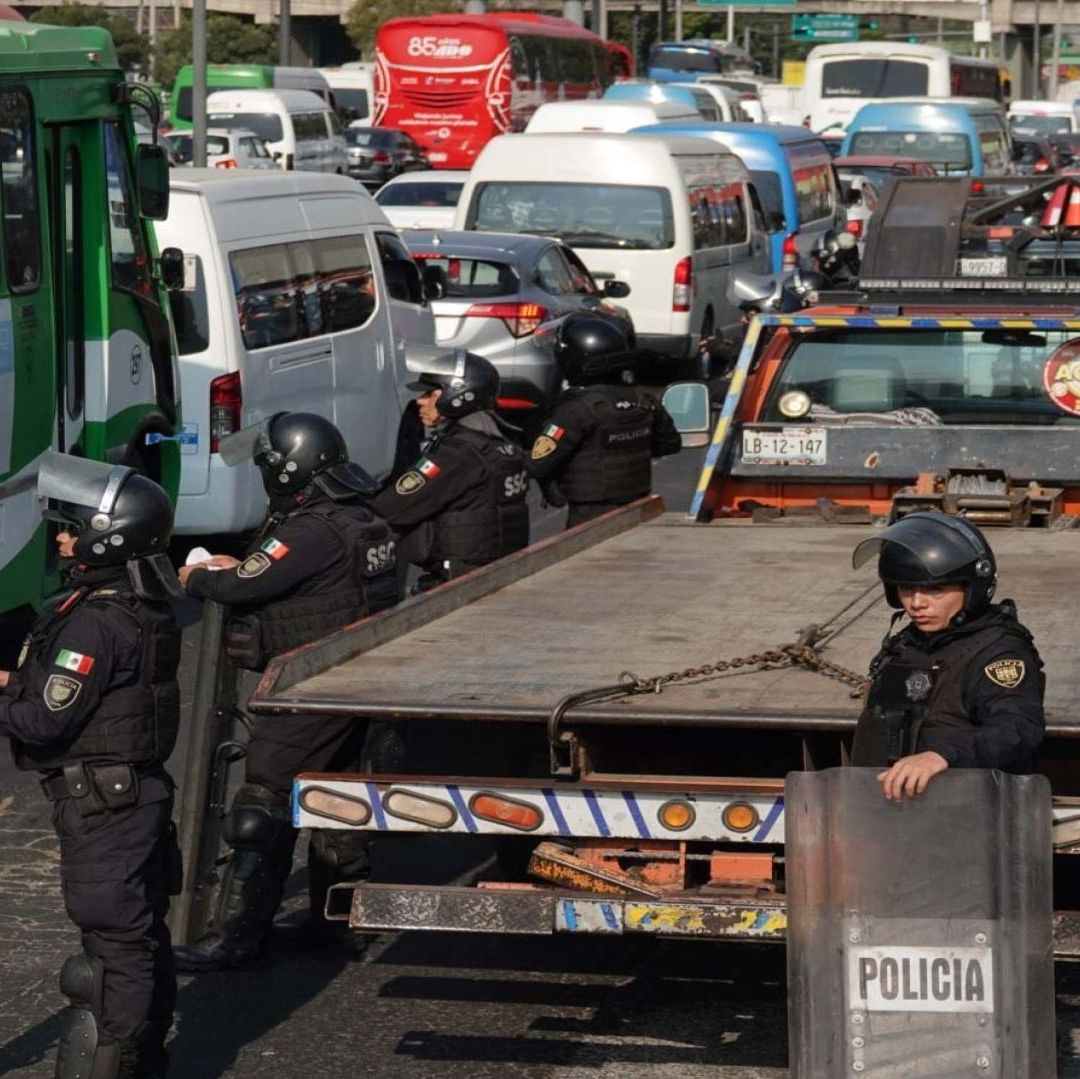 Dos policías al lado de una grúa; hay autos varados.