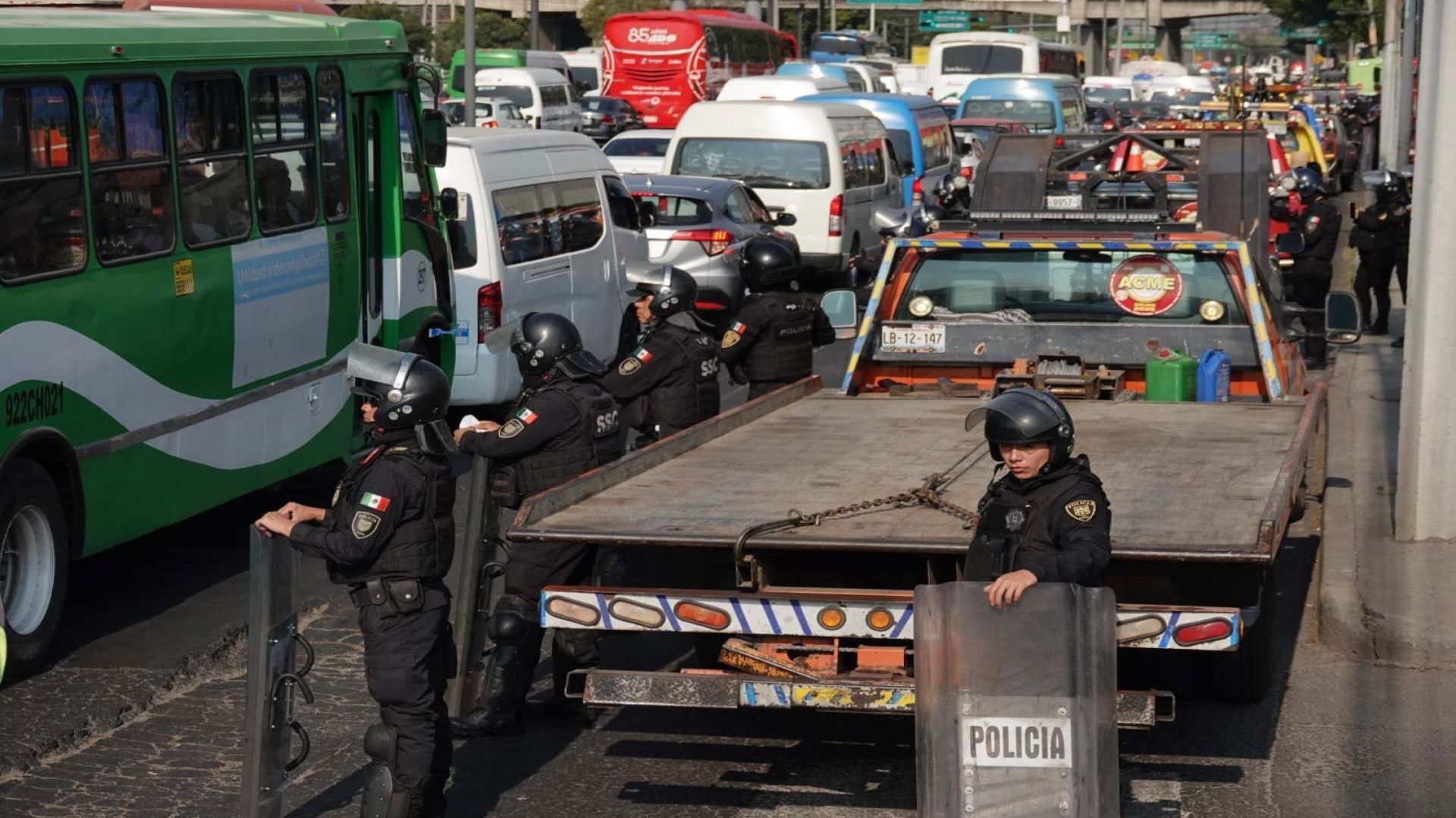 Dos policías al lado de una grúa; hay autos varados.