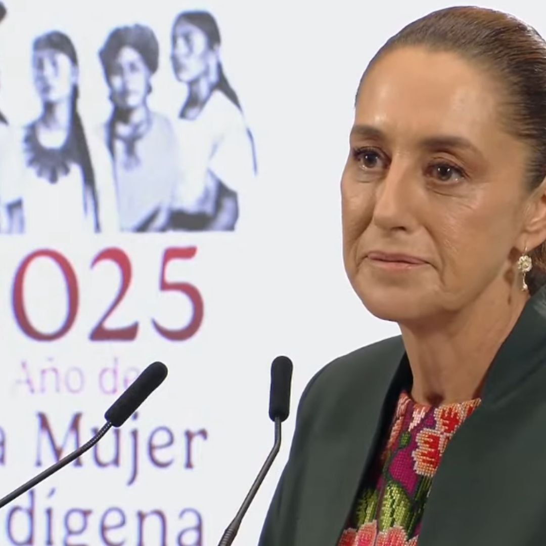 Una mujer viste un traje gris con una blusa de rosas.