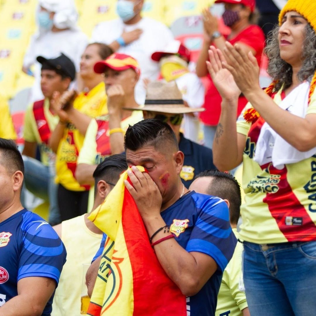 Personas en un estadio de futbol se muestran tristes.
