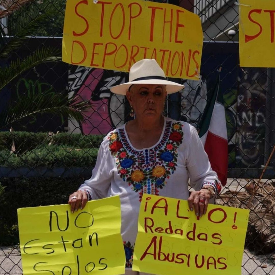 Una mujer con carteles en apoyo a migrantes.