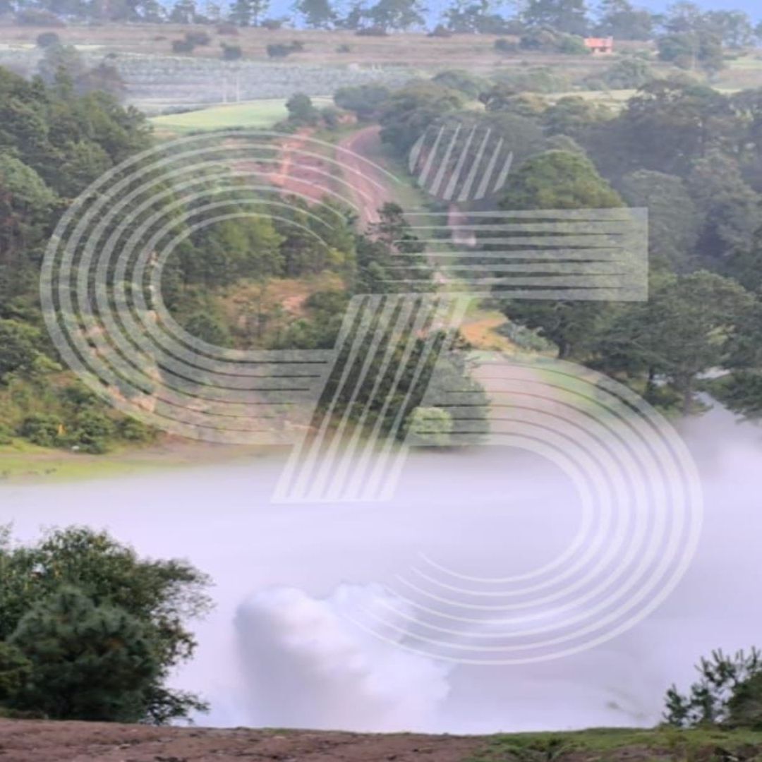 Una columna de humo se puede ver en un paisaje verde.