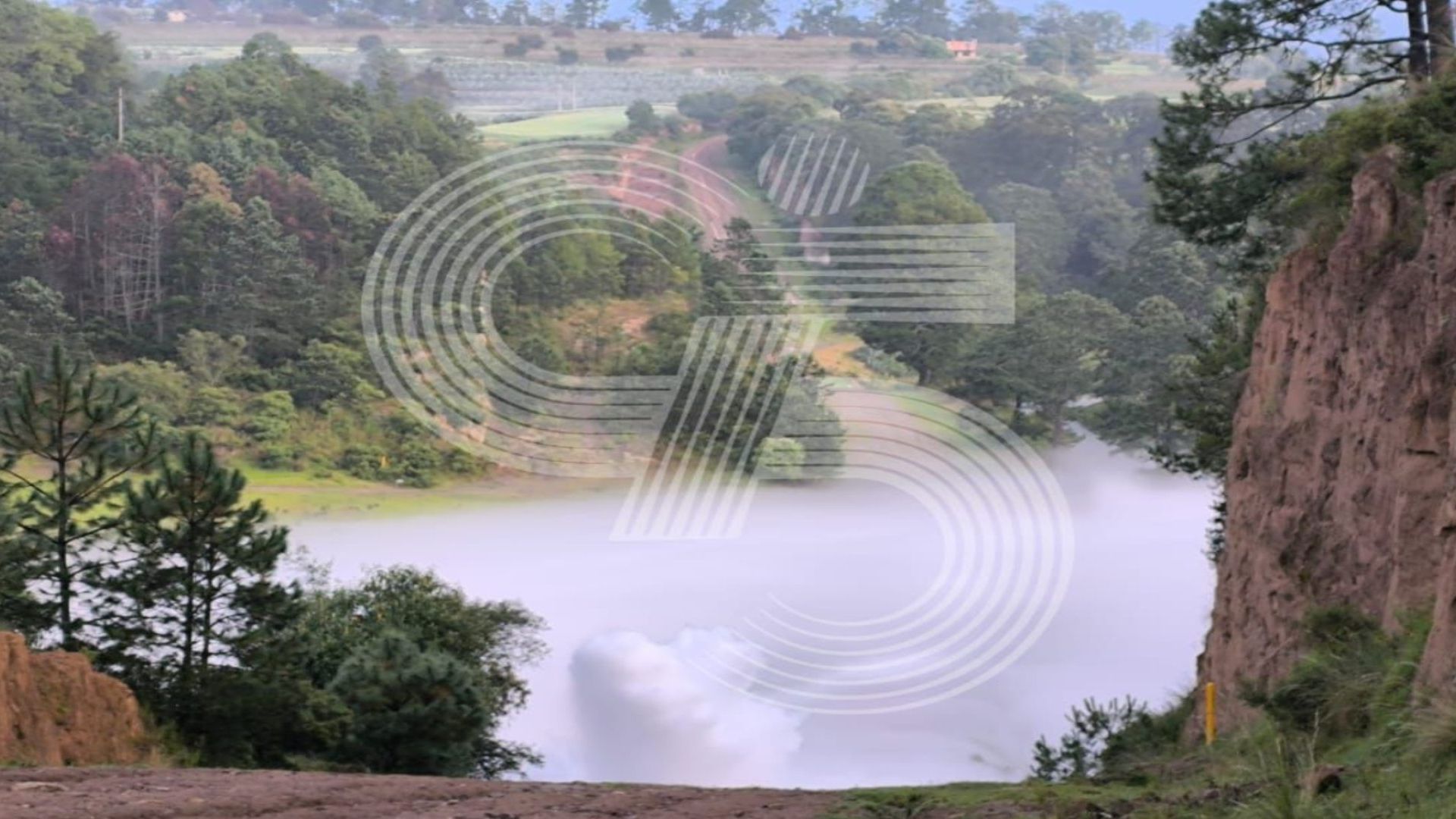 Una columna de humo se puede ver en un paisaje verde.