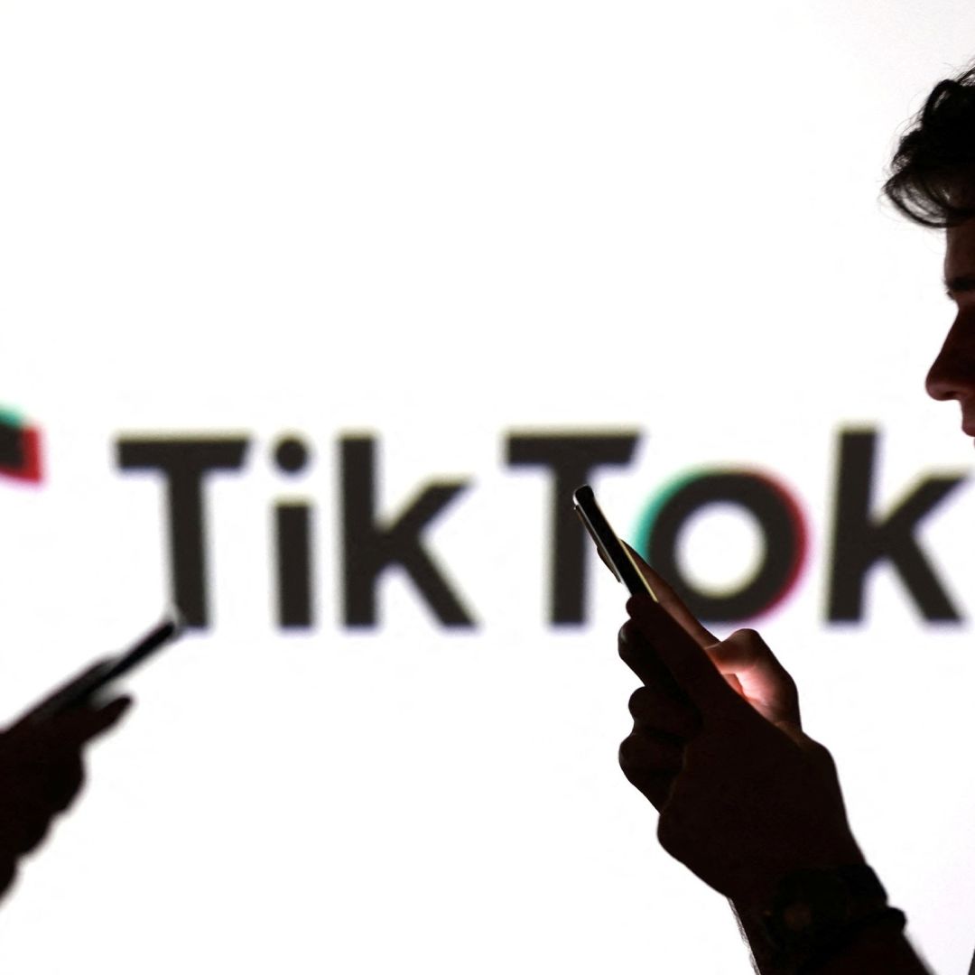 Personas sostienen teléfonos celulares con logo de tiktok de fondo