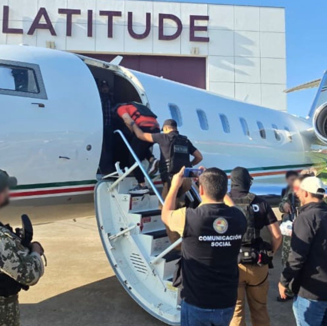 Un hombre es llevado y custodiado en un avión.