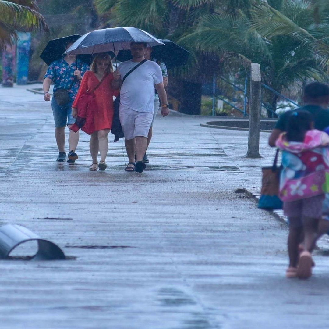 Personas en la playa se cubren con sombrilla de una tormenta.
