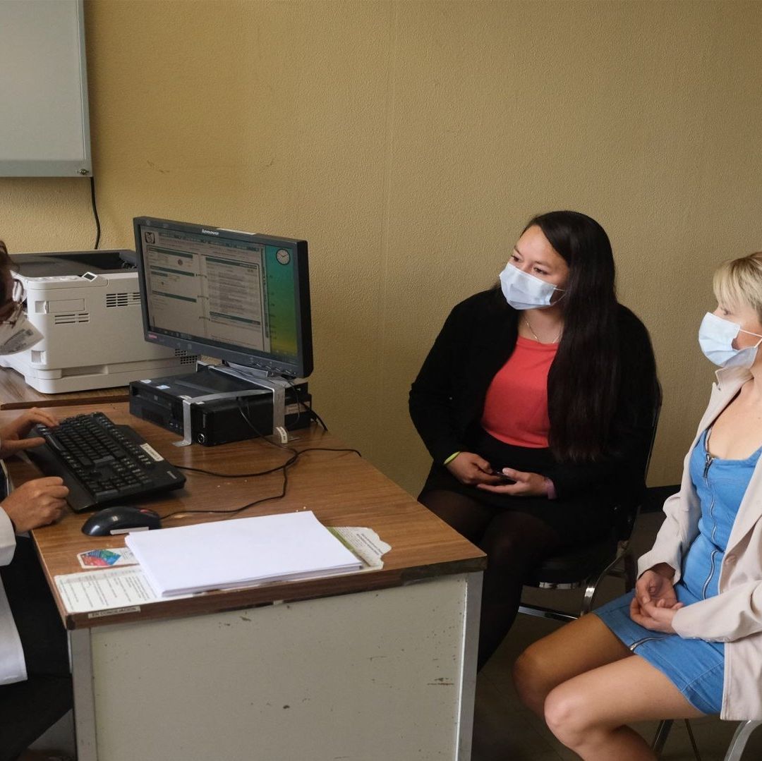 Tres personas frente a una doctora reciben en un consultorio médico.