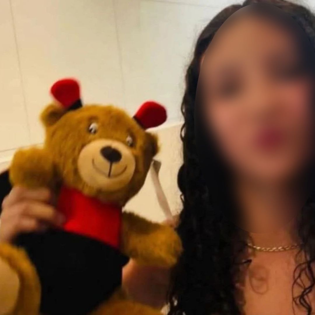 Una mujer con el rostro censurado, tiene un oso de peluche.