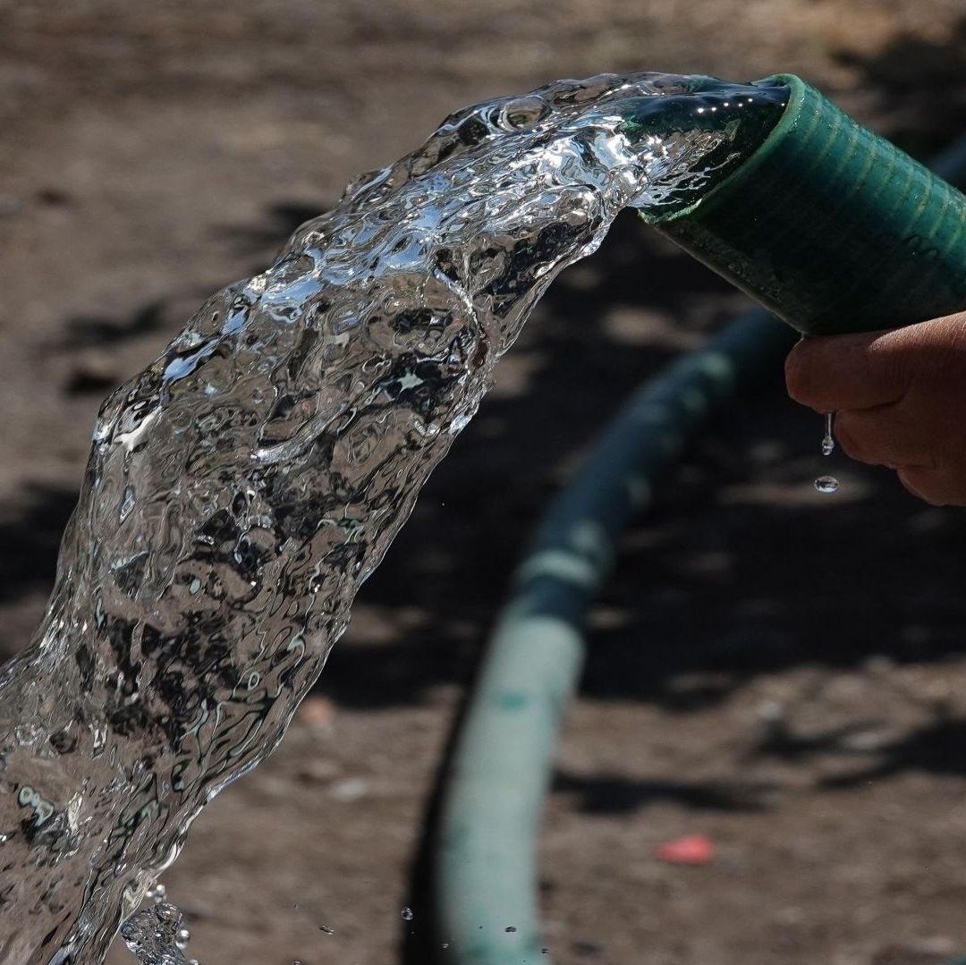 Una persona sosteniendo una manguera de agua.