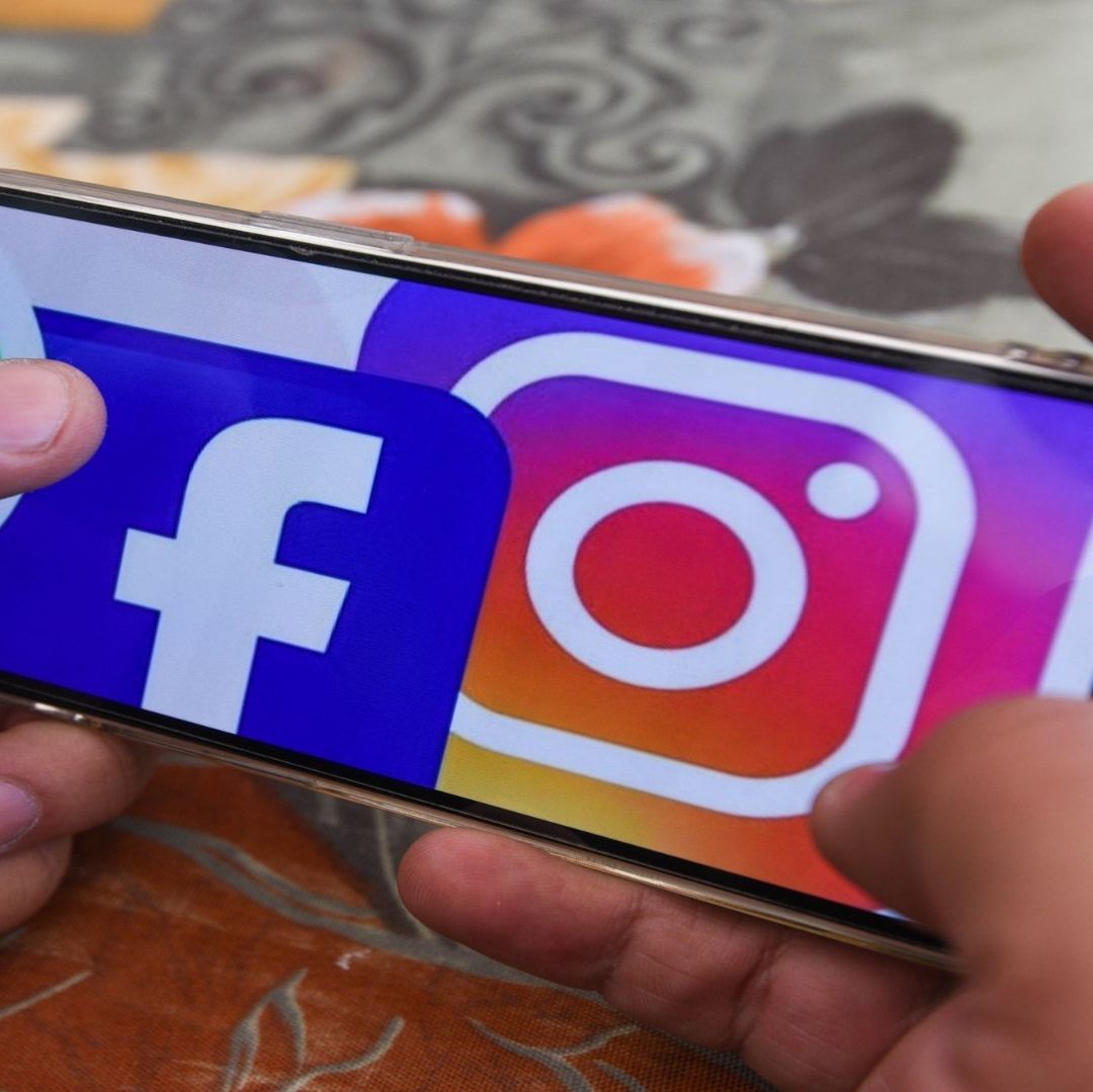 Un hombre sostiene un celular con una imagen de redes sociales.