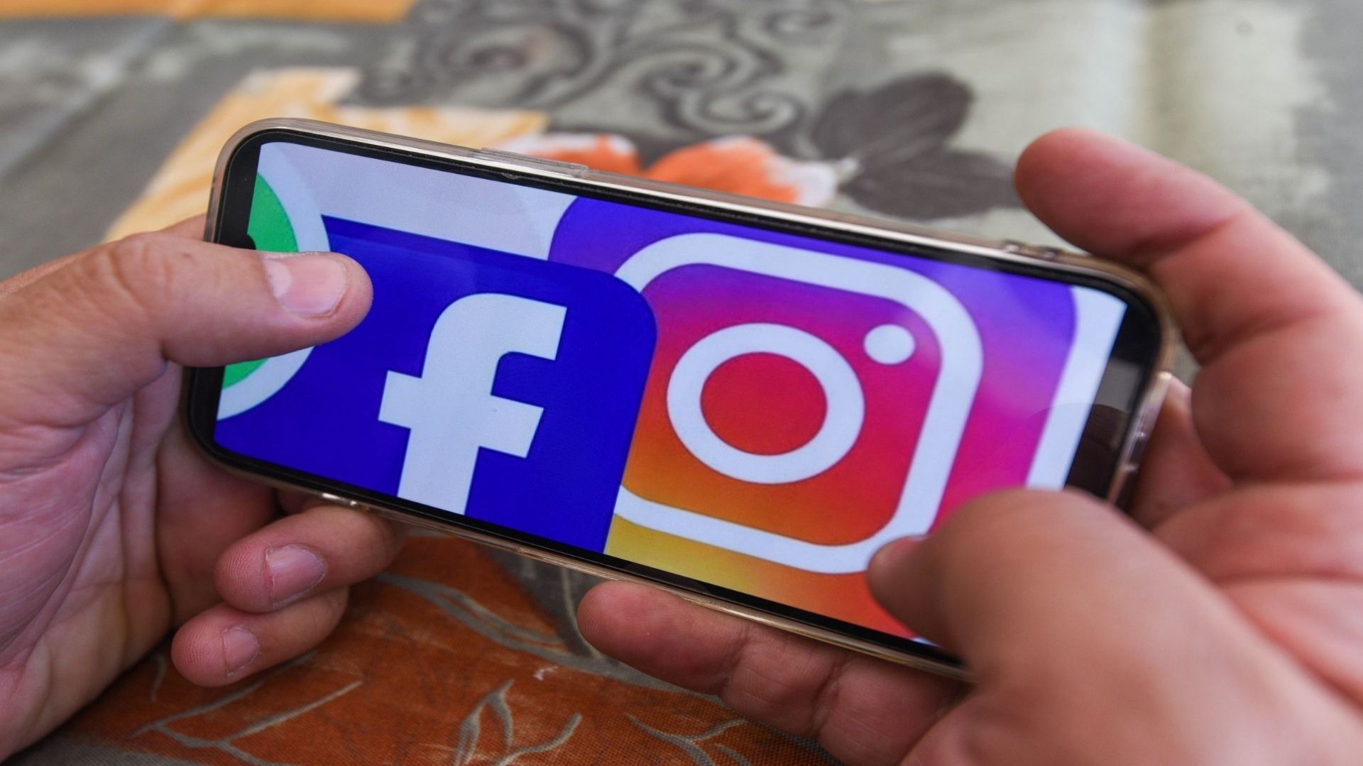 Un hombre sostiene un celular con una imagen de redes sociales.